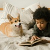 a boy reading a book to a dog