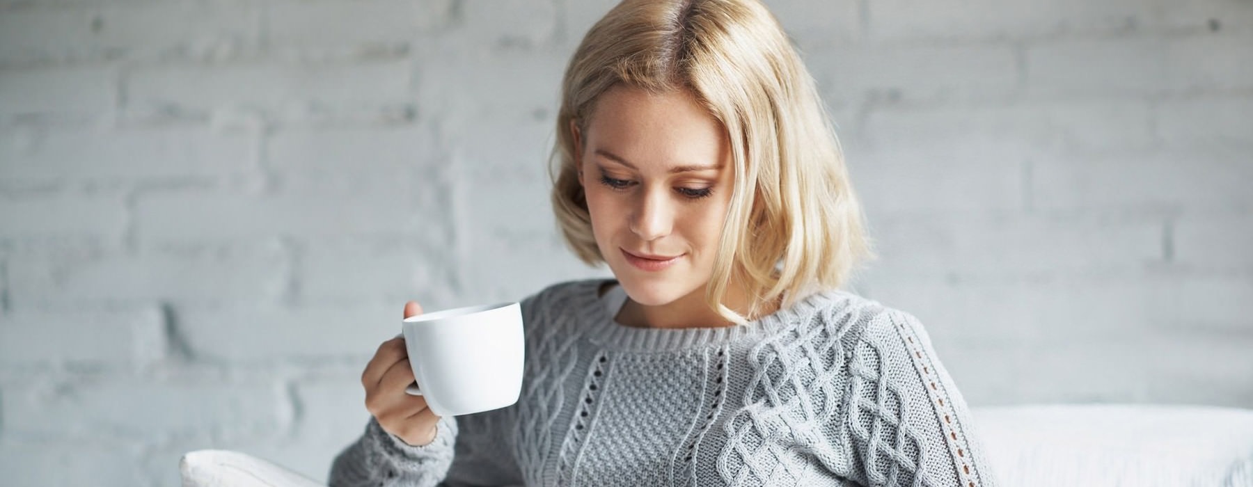 resident reads on her couch with a cup of coffee